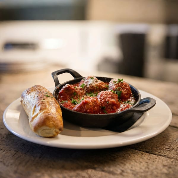 Meatballs in red sauce with parmesan and parsley in a cast iron dish, served with bread.